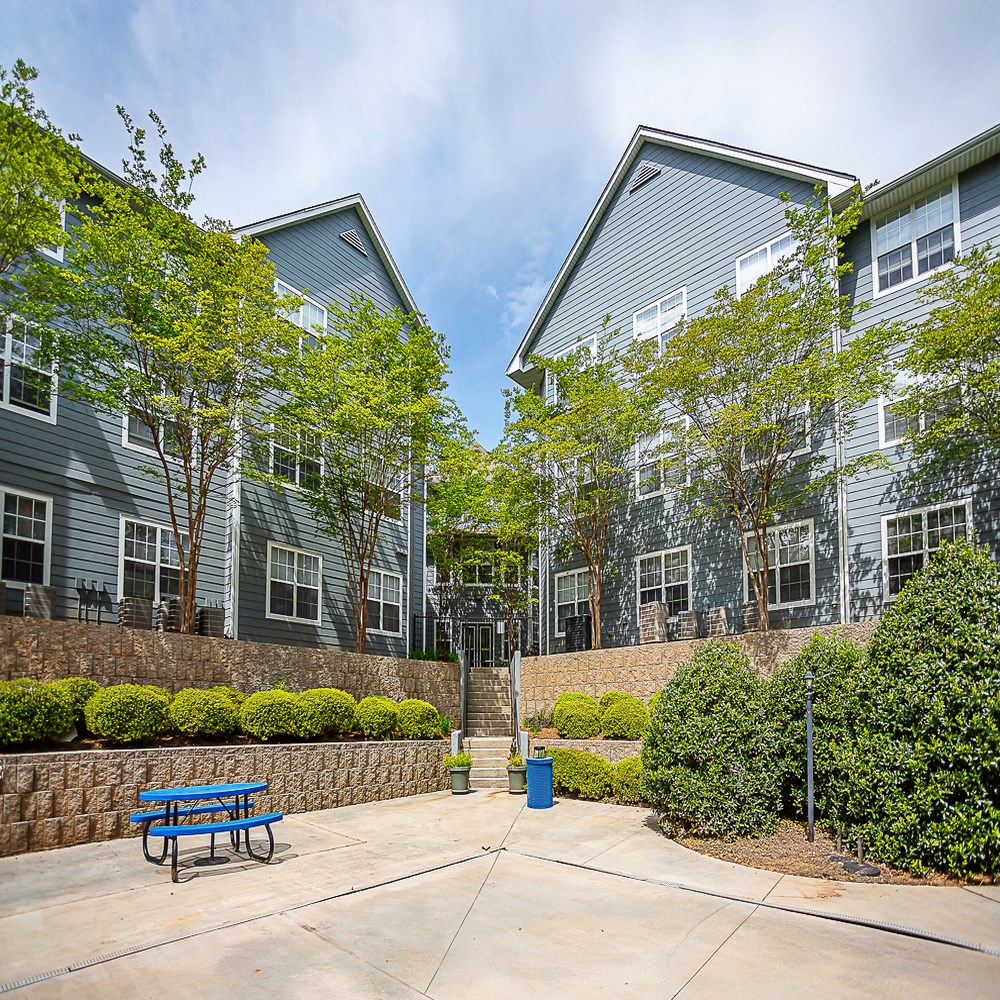 an outdoor patio with a blue bench in front of an apartment building