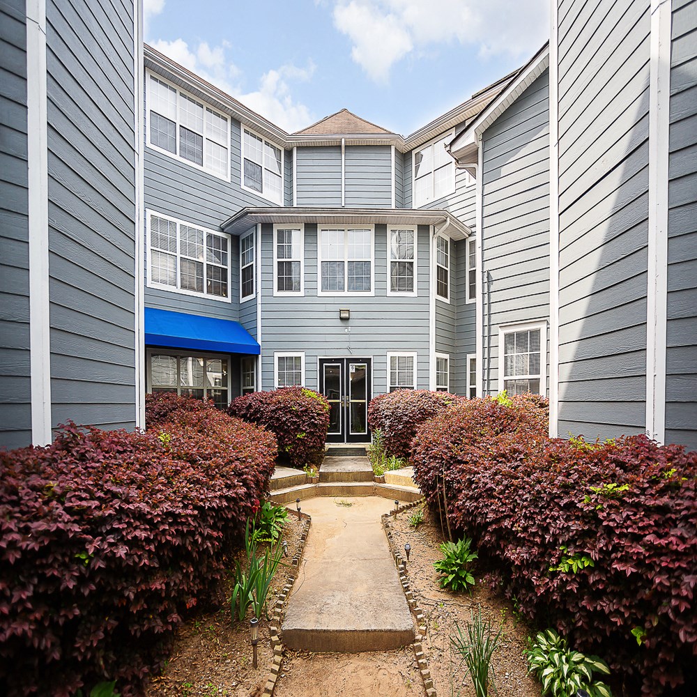a pathway leading to an apartment building with a courtyard