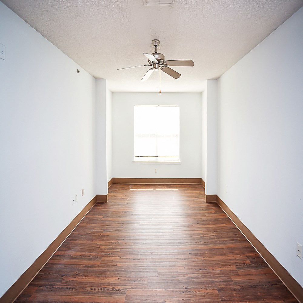an empty room with wooden floors and a ceiling fan