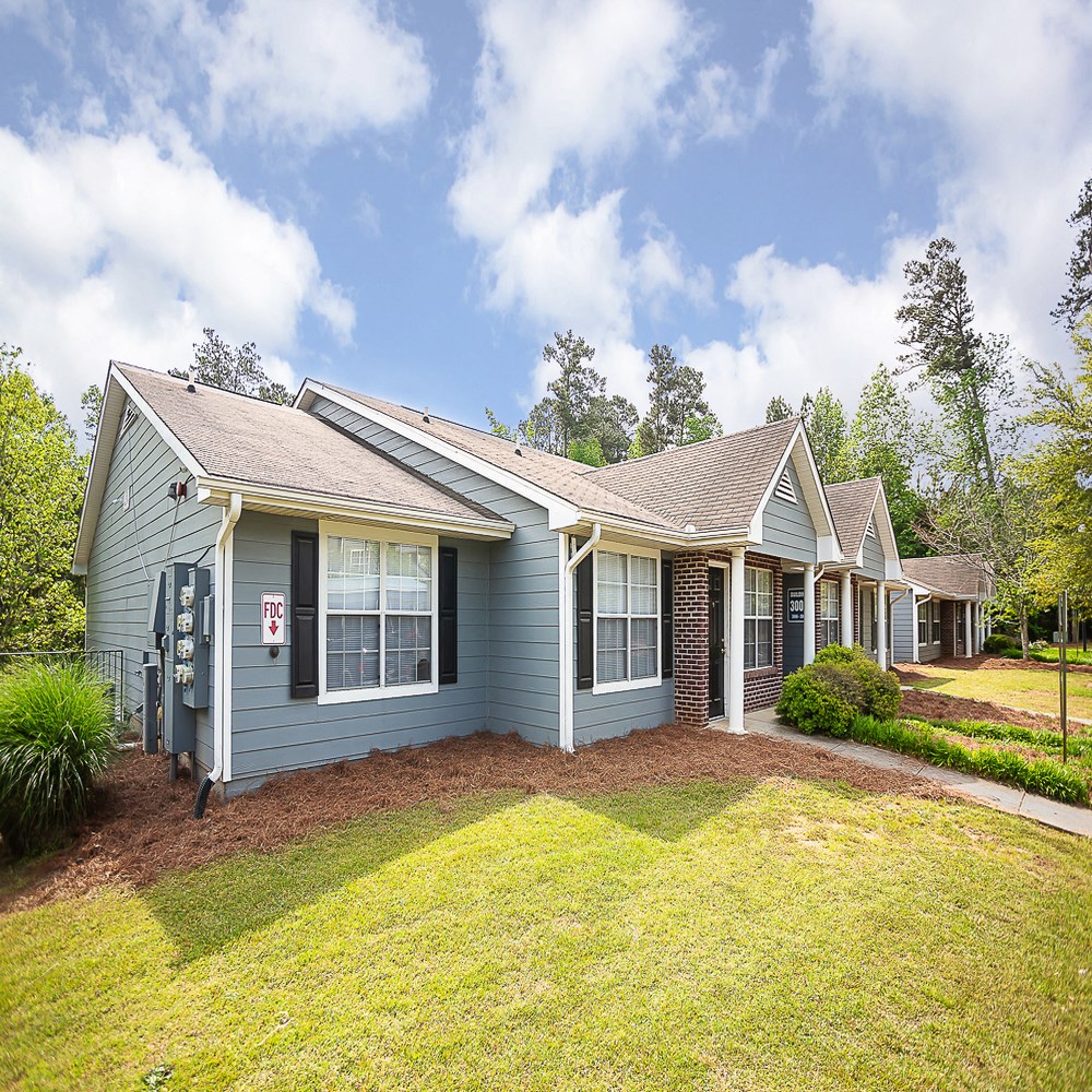 the front of a blue house with a yard and grass