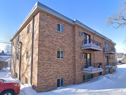 A red car is parked in front of a brick building.