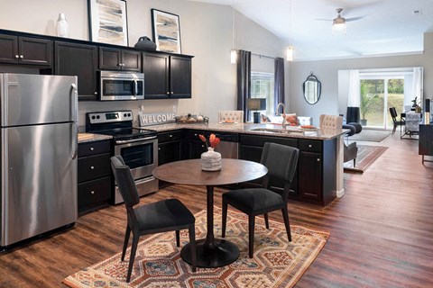 a kitchen with black cabinets and stainless steel appliances and a table