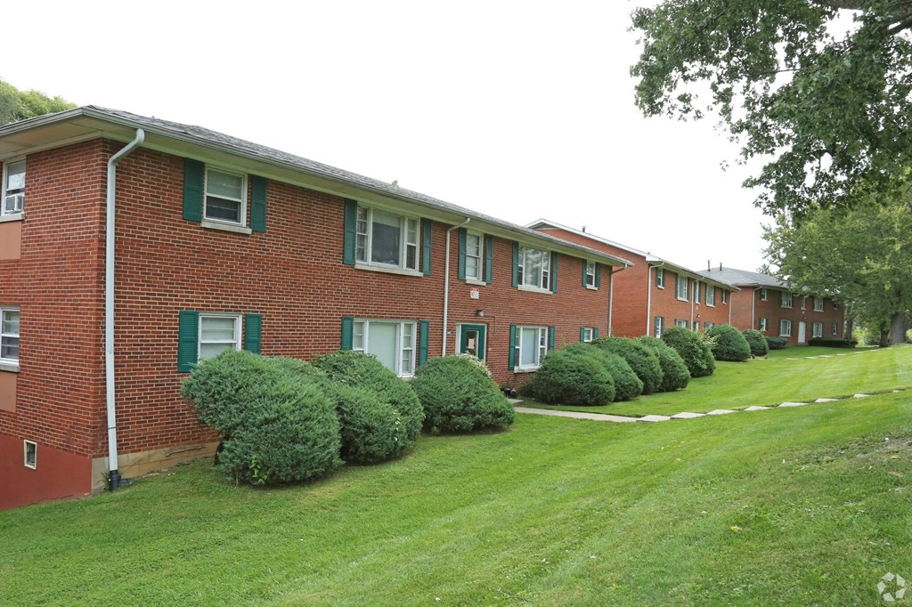 a large brick apartment building with a green lawn
