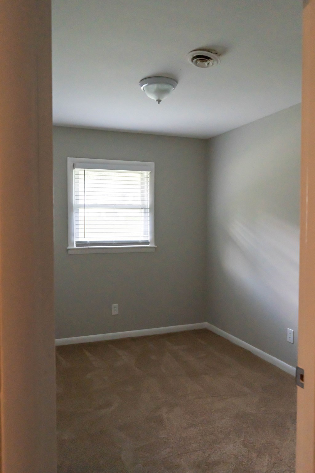 an empty room with a window and a ceiling fan