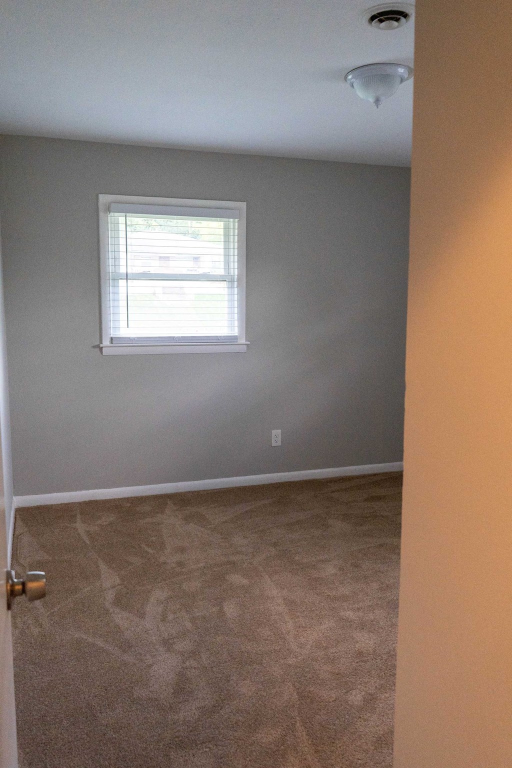 an empty room with a window and a carpeted floor