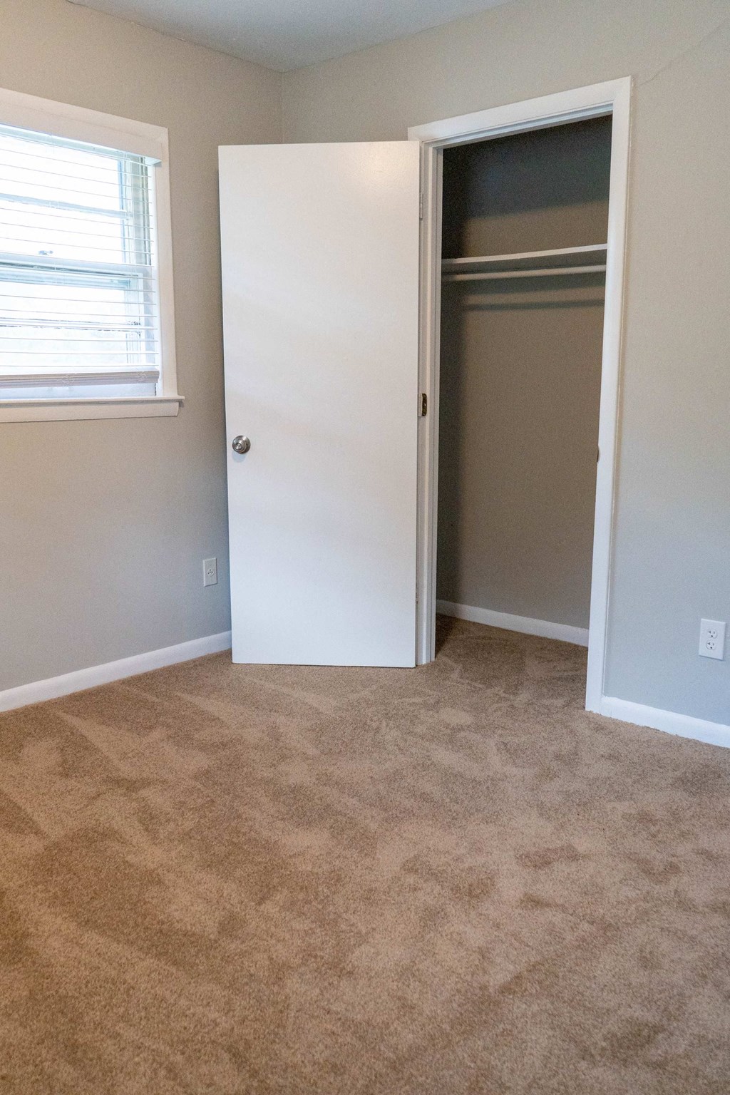 an empty bedroom with a closet and a window