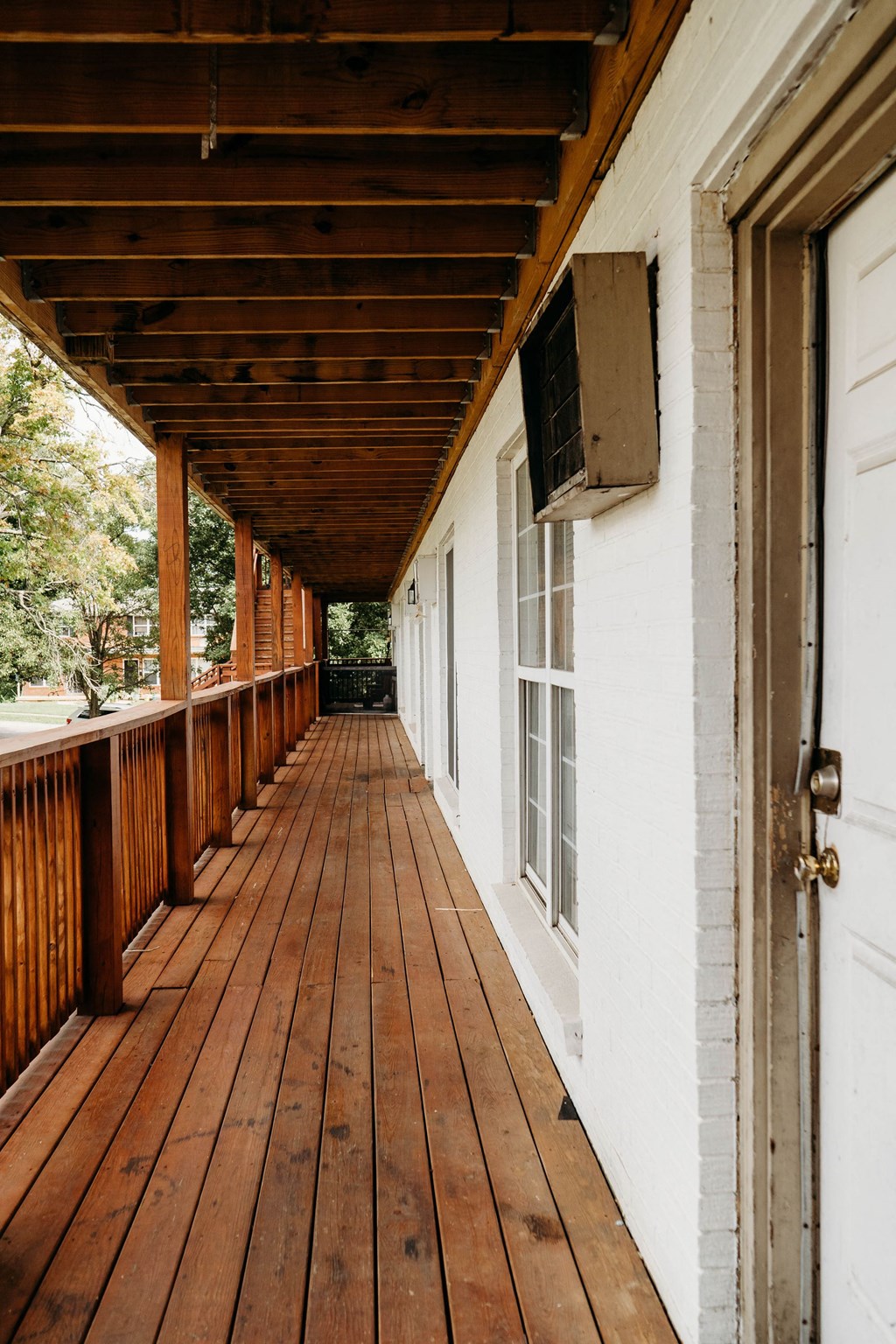 a long porch with wood floors and white walls and a wooden deck