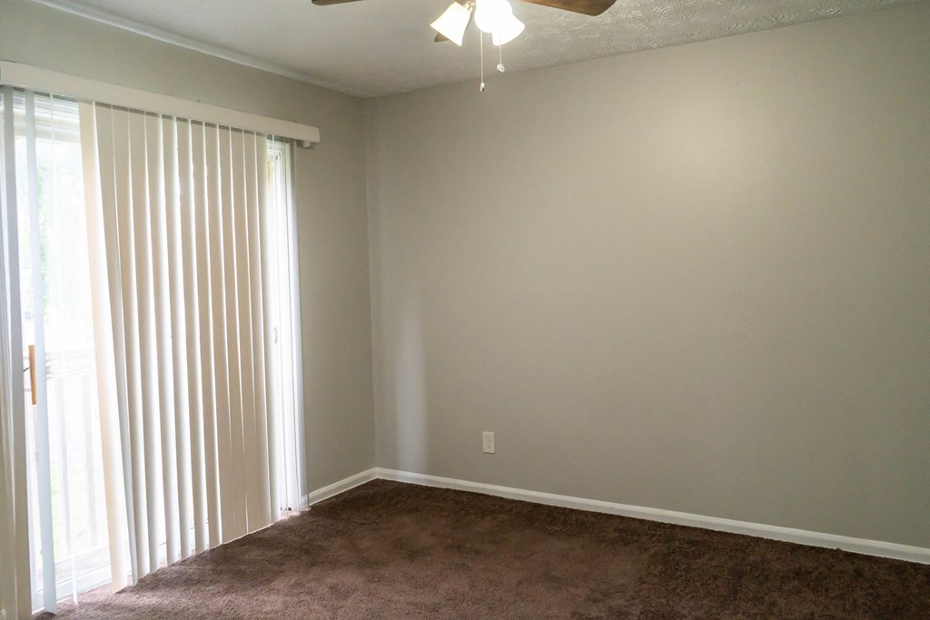 an empty living room with a large window and blinds