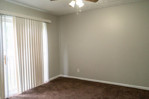 an empty living room with a large window and blinds