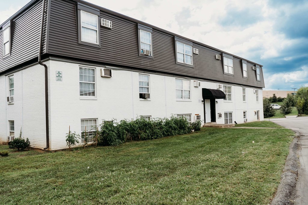 a large white building with a black roof and a lawn