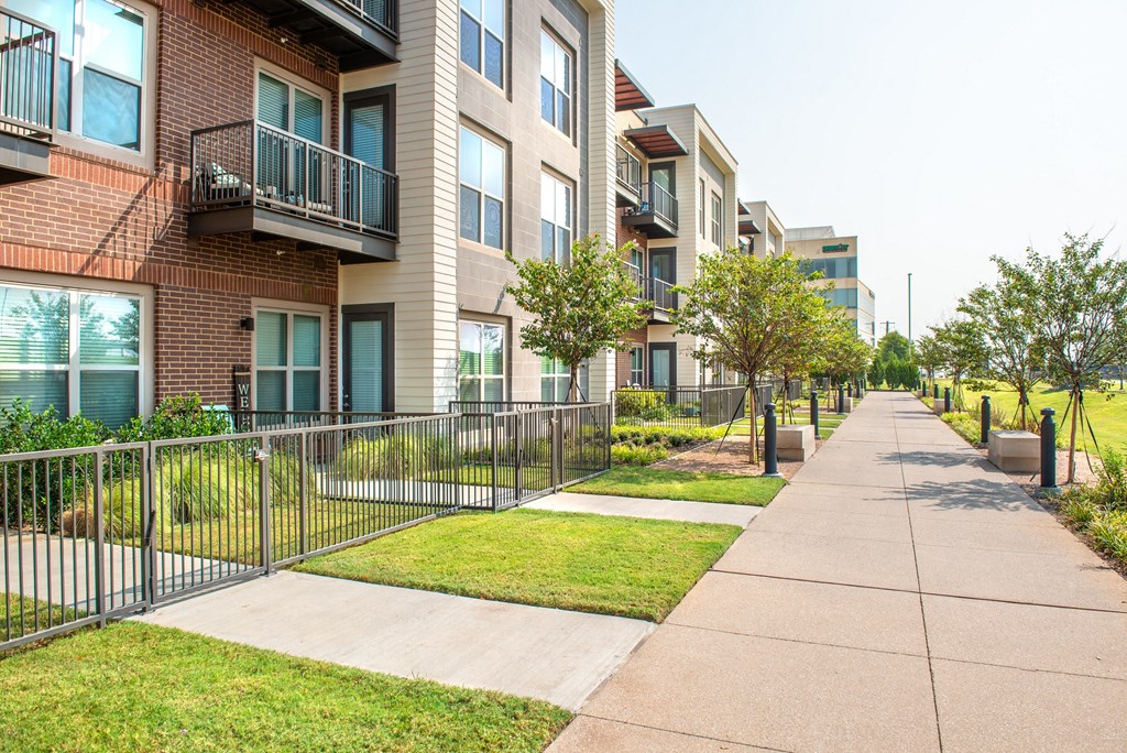 a row of apartments with a sidewalk and a fence