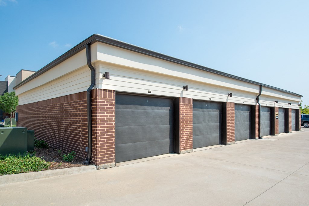the outside of a building with three garages and a sidewalk