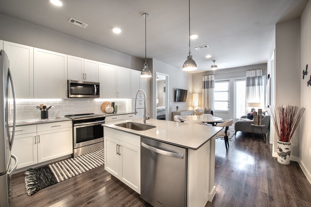 an open kitchen and living room with an island and stainless steel appliances