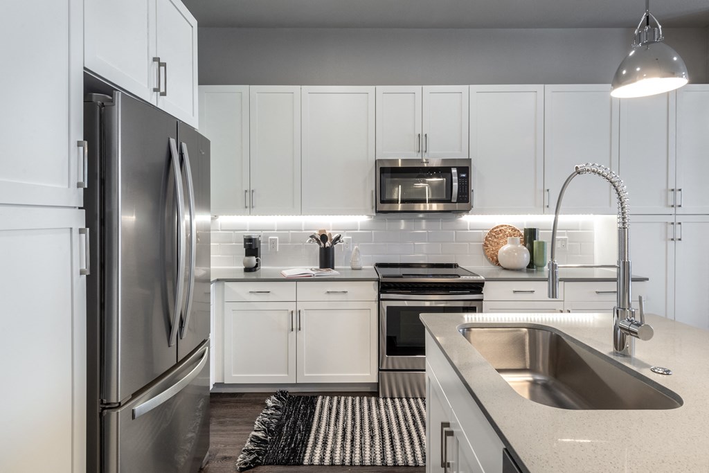 a white kitchen with stainless steel appliances and white cabinets