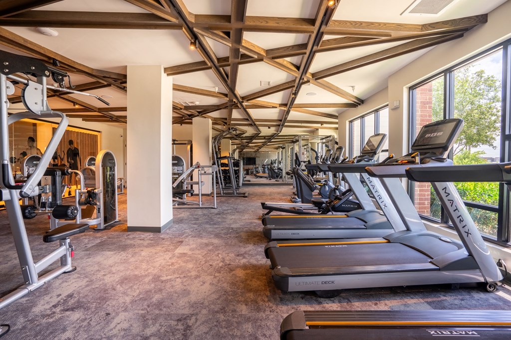 a gym with treadmills and other exercise equipment in a building with windows