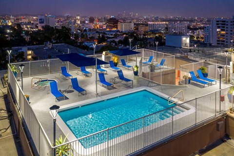 a pool on the rooftop of a hotel overlooking a city at night