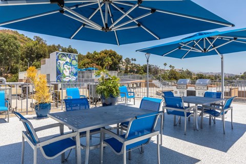 a patio with blue tables and chairs and blue umbrellas