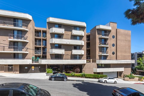 an apartment building on the corner of a street with cars