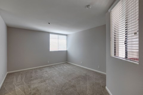 an empty living room with a window and carpet