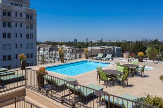 Apartments in Hancock Park, CA - Elevated View of Rooftop Pool and Patio with Jacuzzi, Lounge Chairs and Tables