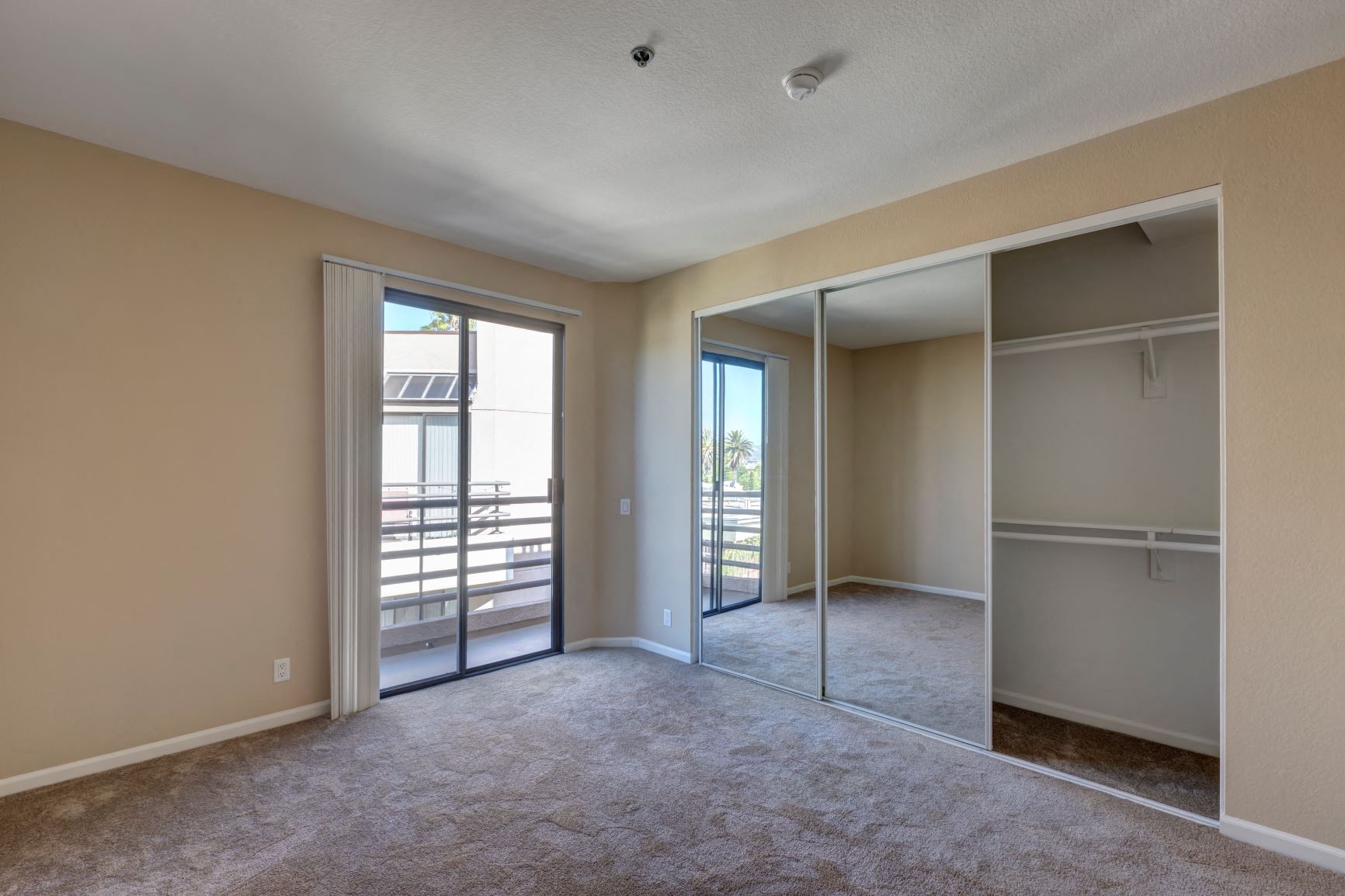 One Bedroom Apartments in Hancock Park, CA - Apartment Carpeted Bedroom with Mirrored Closet and Sliders to Balcony