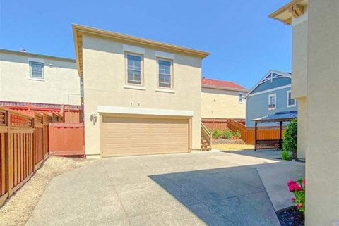 A beige house with a brown garage door and a red fence.