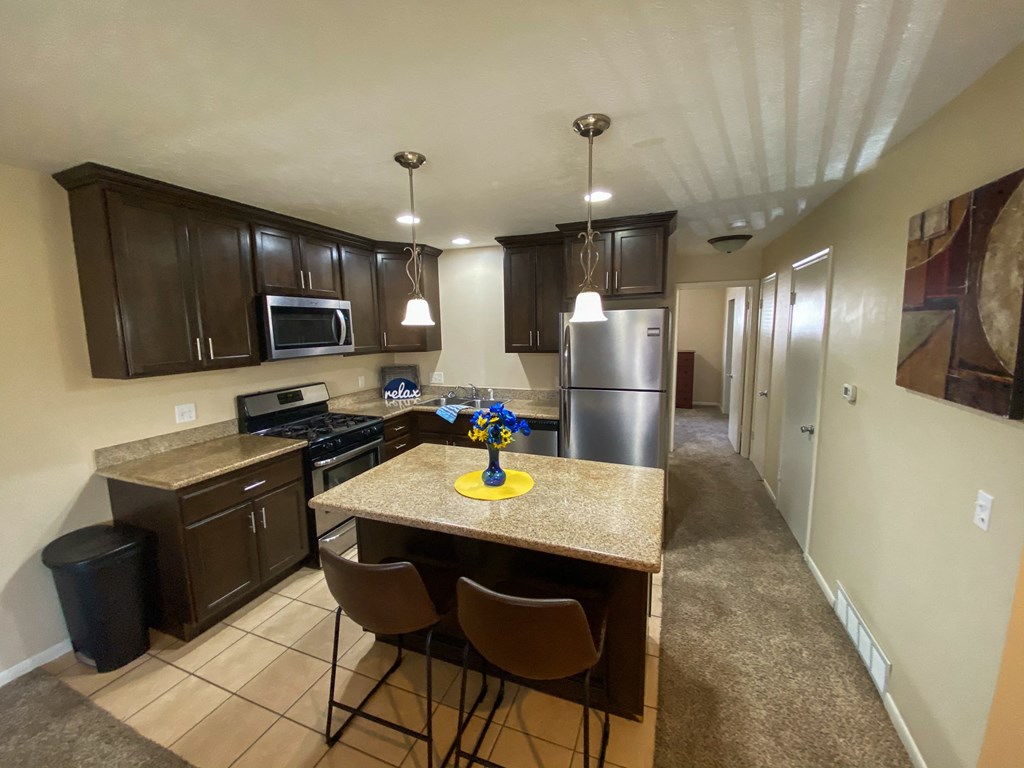 full kitchen with granite countertops and stainless steel appliances and a breakfast bar