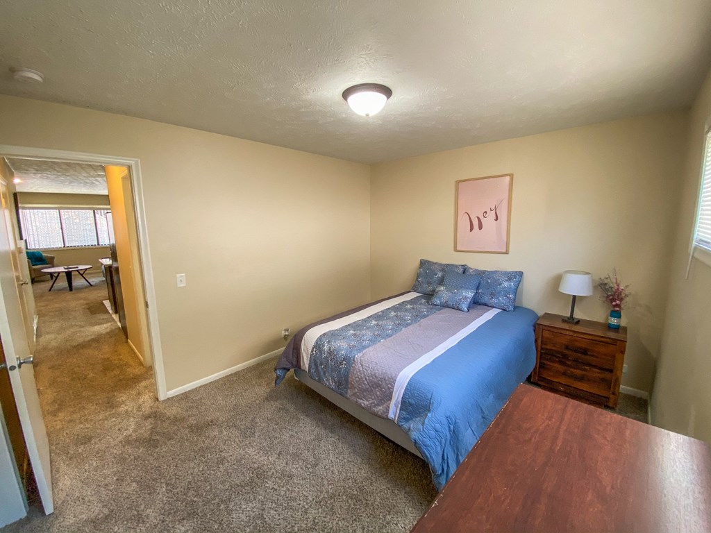 a bedroom with a bed and a door to a living room