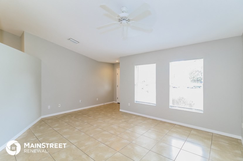 a spacious living room with tile flooring and a ceiling fan