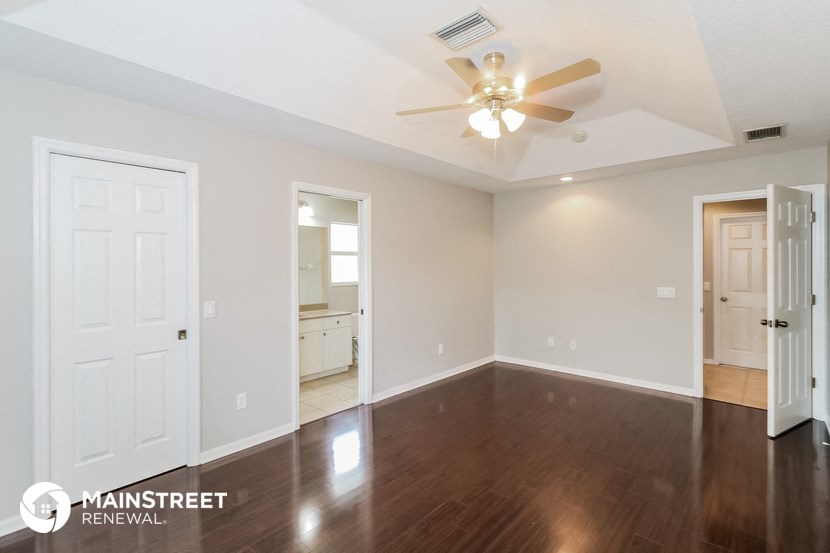 an empty living room with wood flooring and a ceiling fan