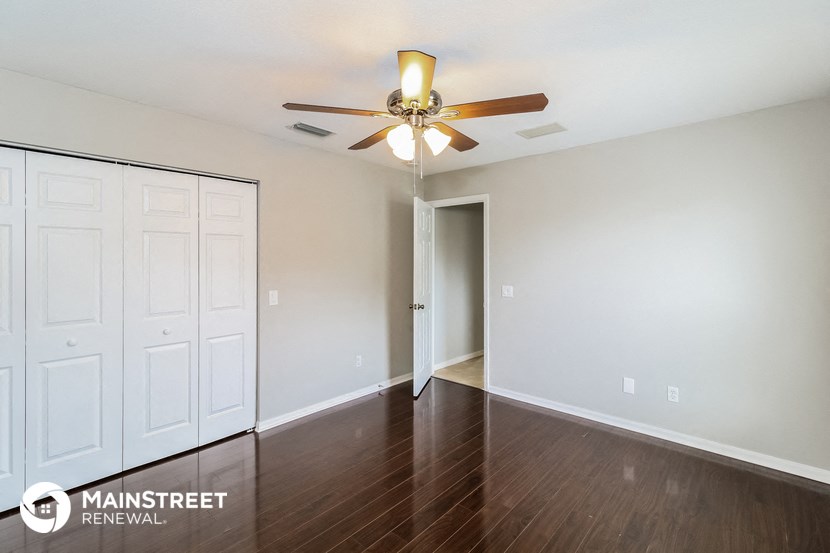 a living room with a ceiling fan and a door to a closet