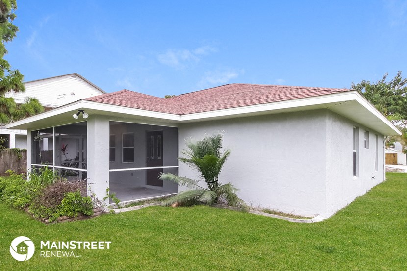 a small white house with a lawn and a palm tree