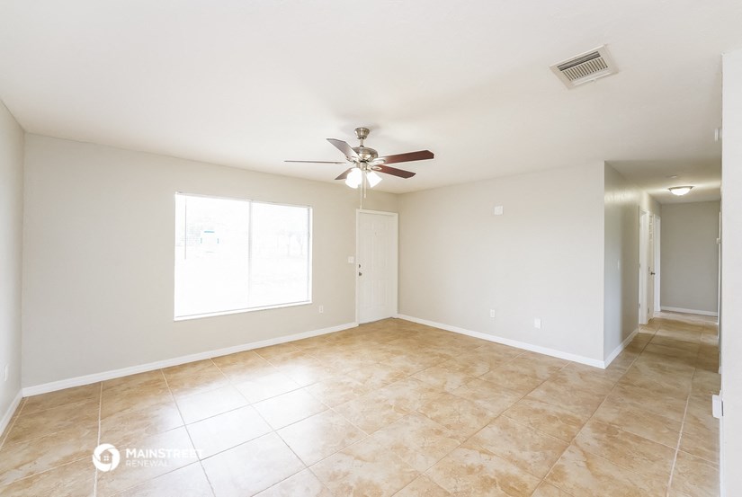 the spacious living room with tile flooring and a ceiling fan