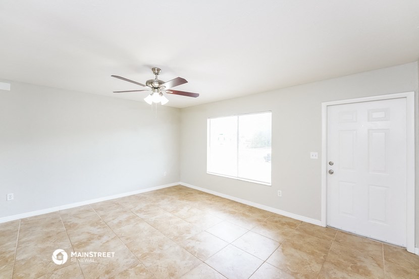 the spacious living room with ceiling fan and tile flooring