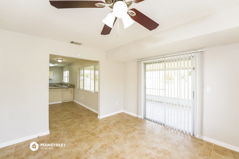 an empty living room with a ceiling fan and a window