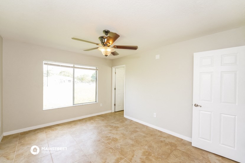 the spacious living room with ceiling fan and tile flooring