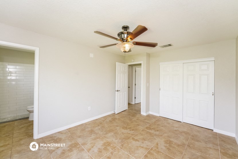 the spacious living room with ceiling fan and tile flooring