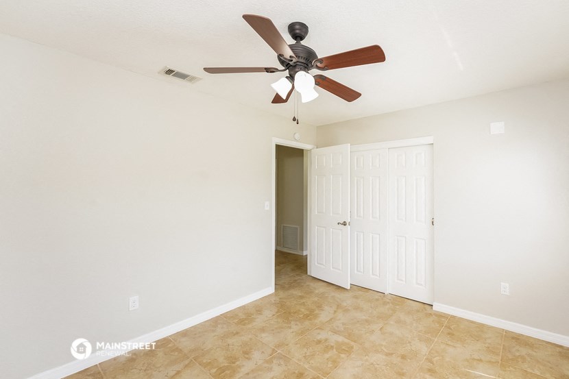 the spacious living room with ceiling fan and tile flooring