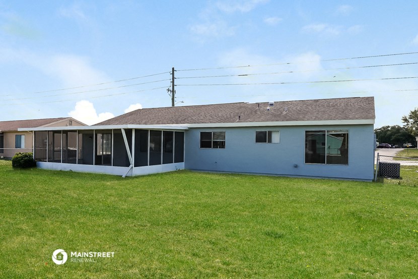 the back of a white house with a grassy yard