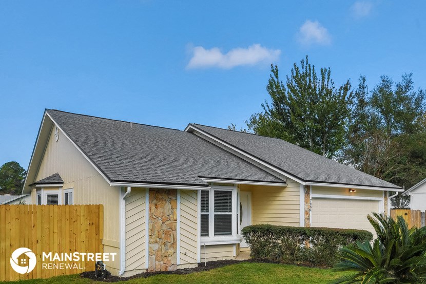 a small white house with a wood fence and grass