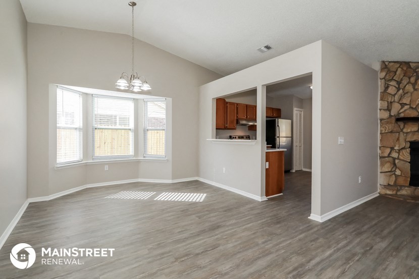 an empty living room with a stone wall and a kitchen