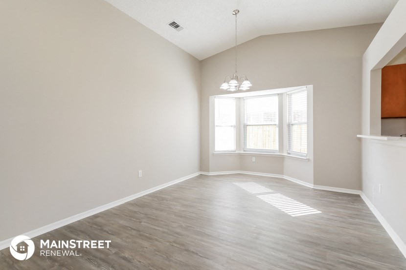 the spacious living room with a large window and wood flooring