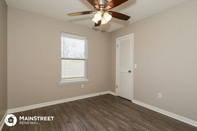 the spacious living room of a home with a ceiling fan