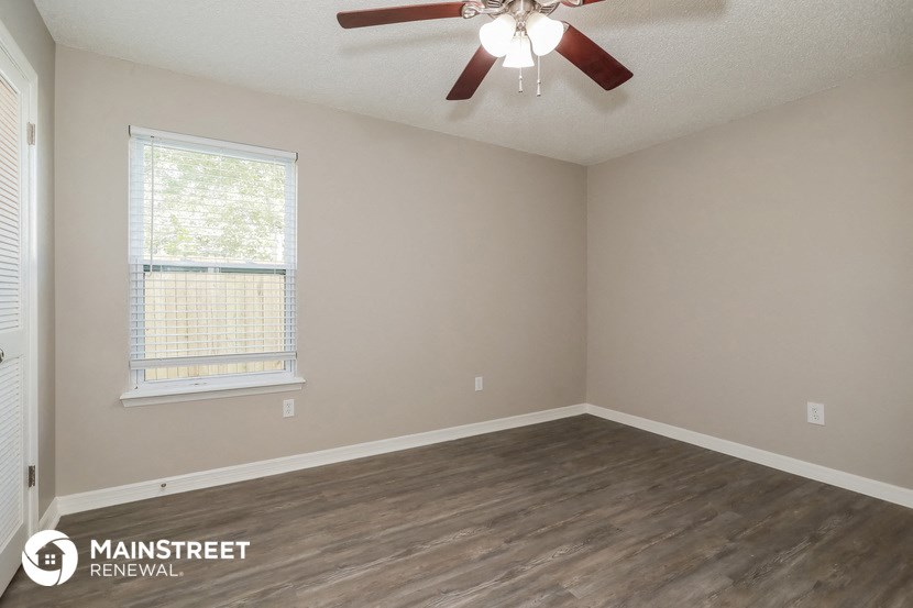 the interior of an empty room with a ceiling fan and a window