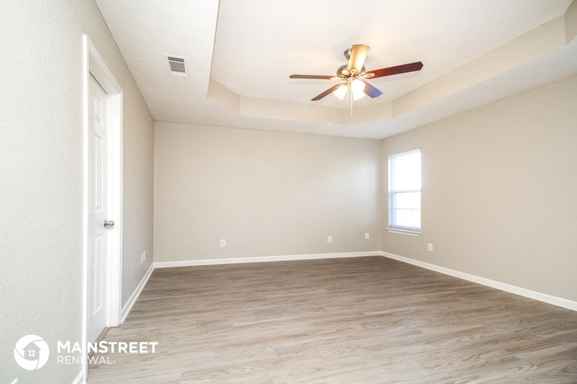 an empty room with a ceiling fan and a window
