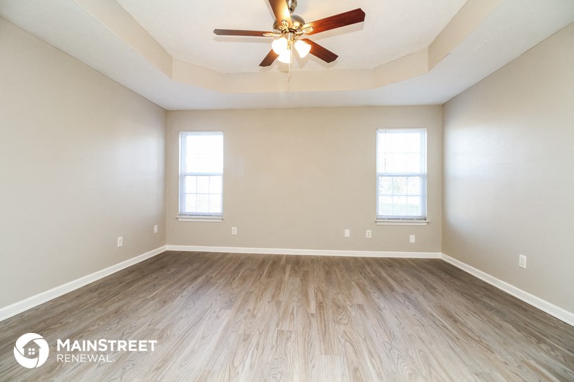 the spacious living room with hardwood floors and a ceiling fan