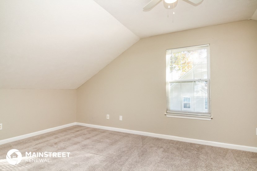 the upstairs bedroom with carpeted floors and a window