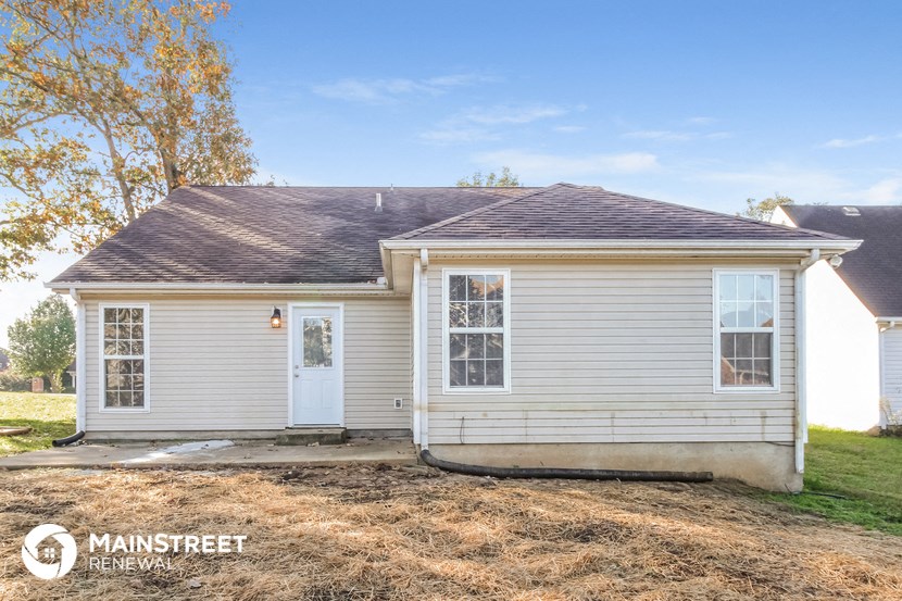 the front exterior of a small white house with a white door