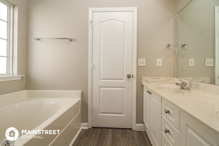 a white bathroom with a tub and a sink and a mirror