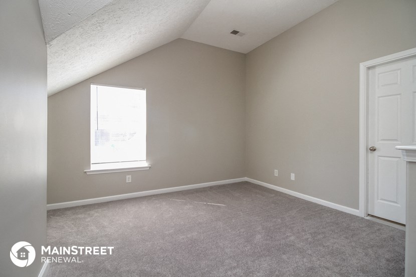 a bedroom with a carpeted floor and a window